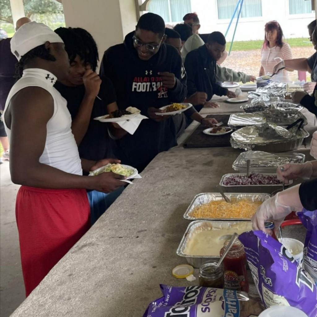 Boys High school dorm line up to get their burrito bowl outside under the pavilion.