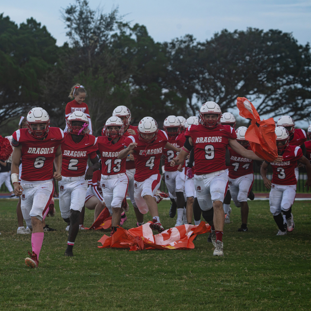 Group of FSDB football players running through the sign on the field. 