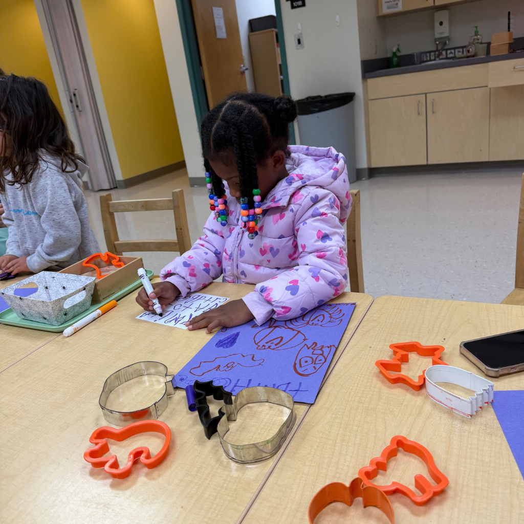 ELC student traces and draws halloween shapes on a paper. 
