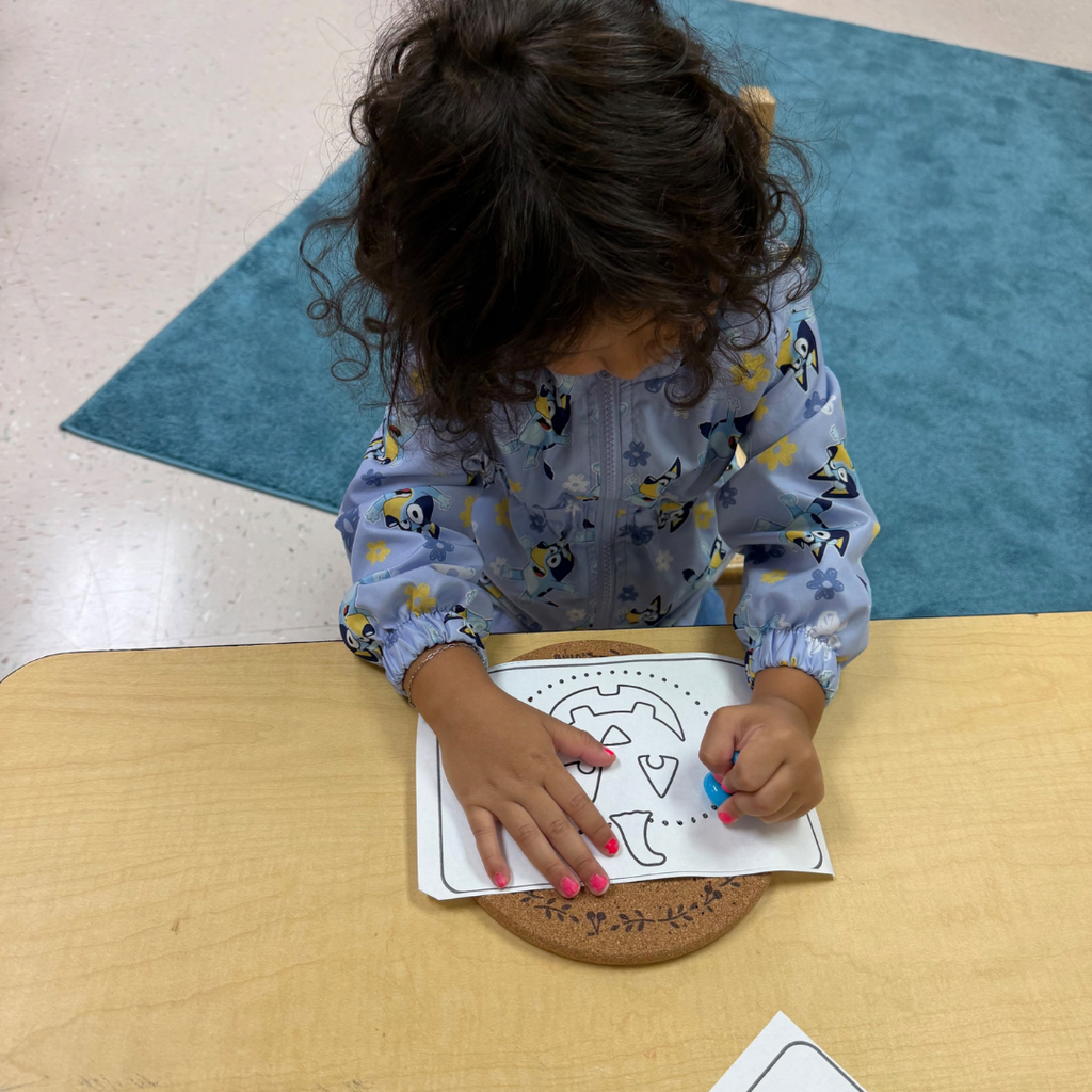 ELC student colors a pumpkin at the table. 