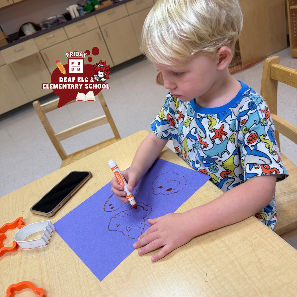ELC student draws halloween cutouts at a table. 
