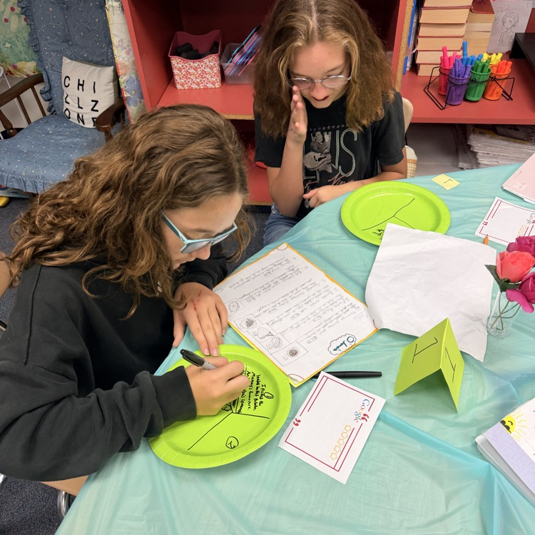 students writing on their paper plates after choosing the food 