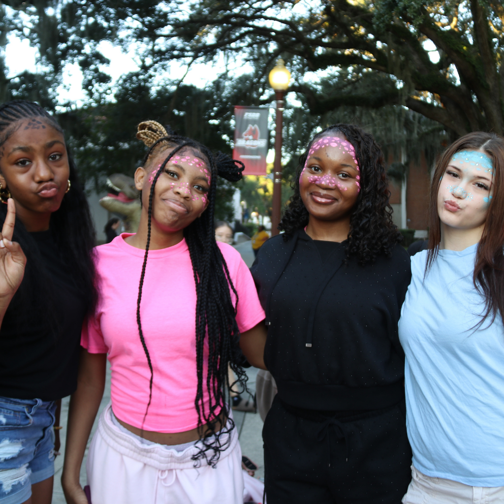 Group of students dressed like dragons smile for a photo outside.