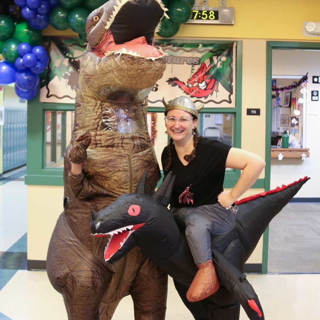 The principals of DHS are wearing blow up dragon costumes smile for a photo in the hallway of Pope.