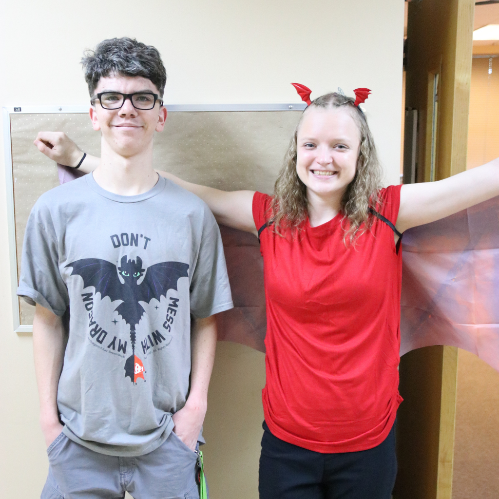 Two students smile for a photo dressed like dragons.