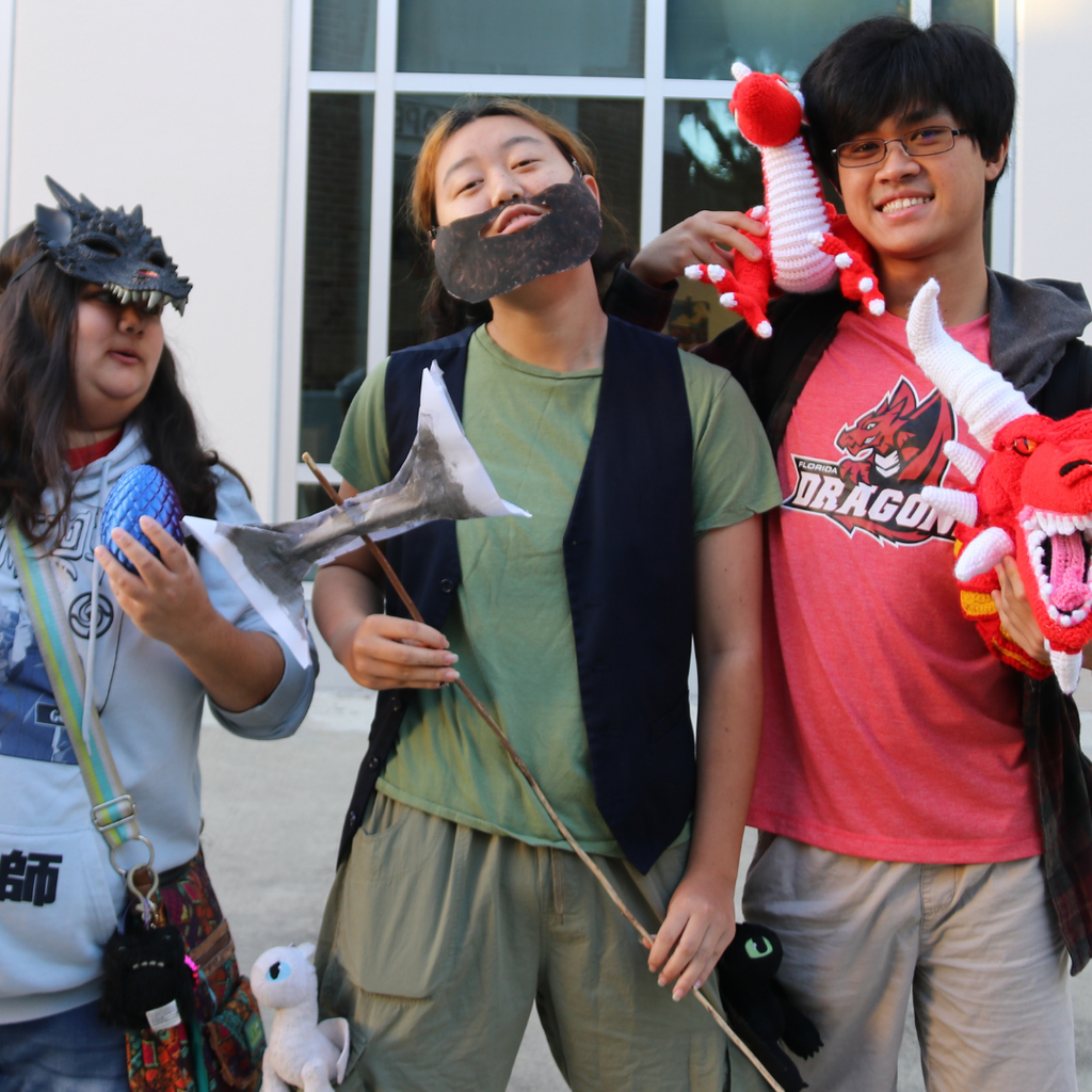 Three students dressed like dragons and vikings pose for a photo.