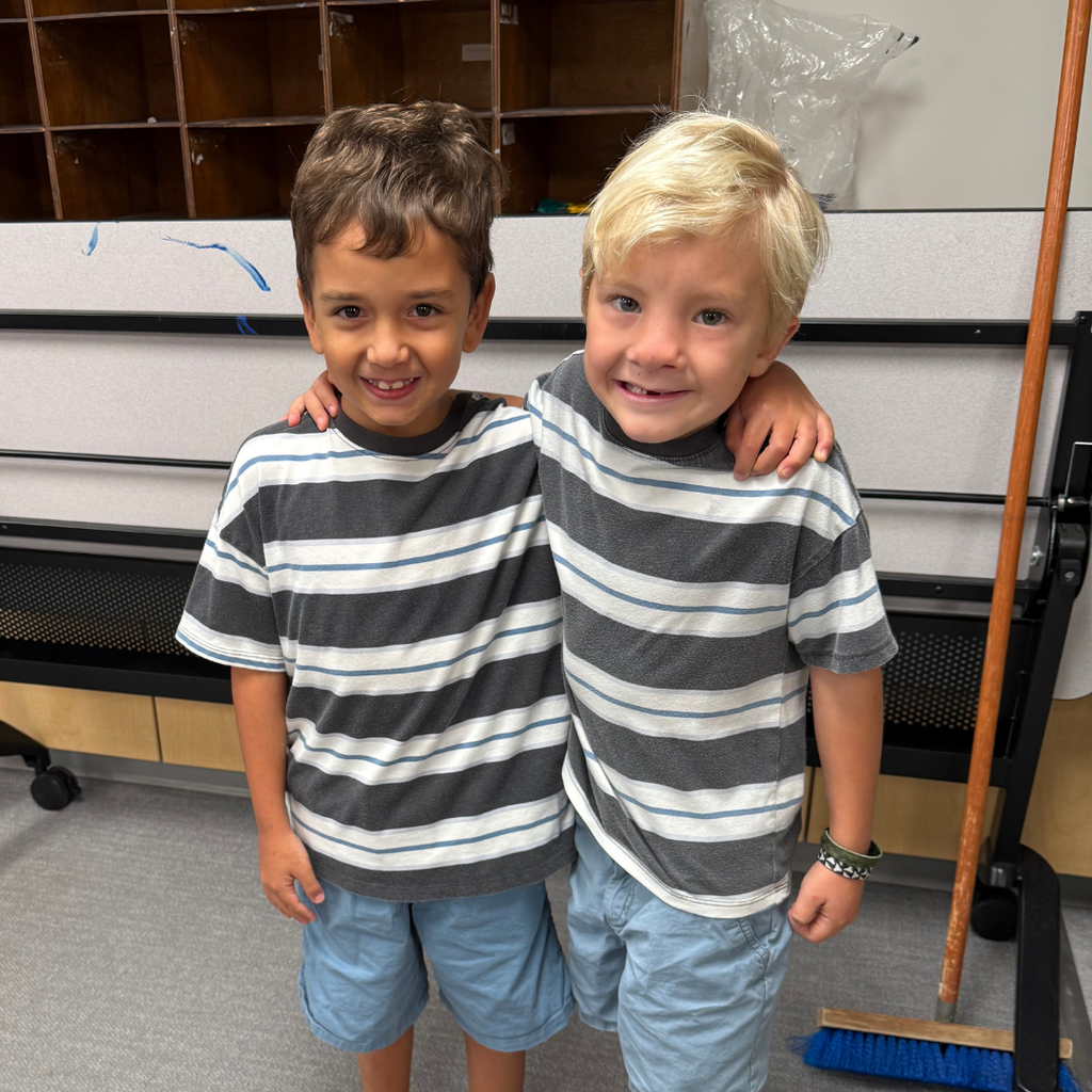 Two students match in stripe black shirts and blue shorts. 