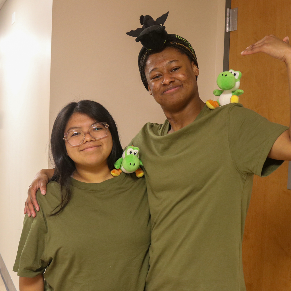 Two students wearing olive green shirts and Yoshi on their shoulder. 