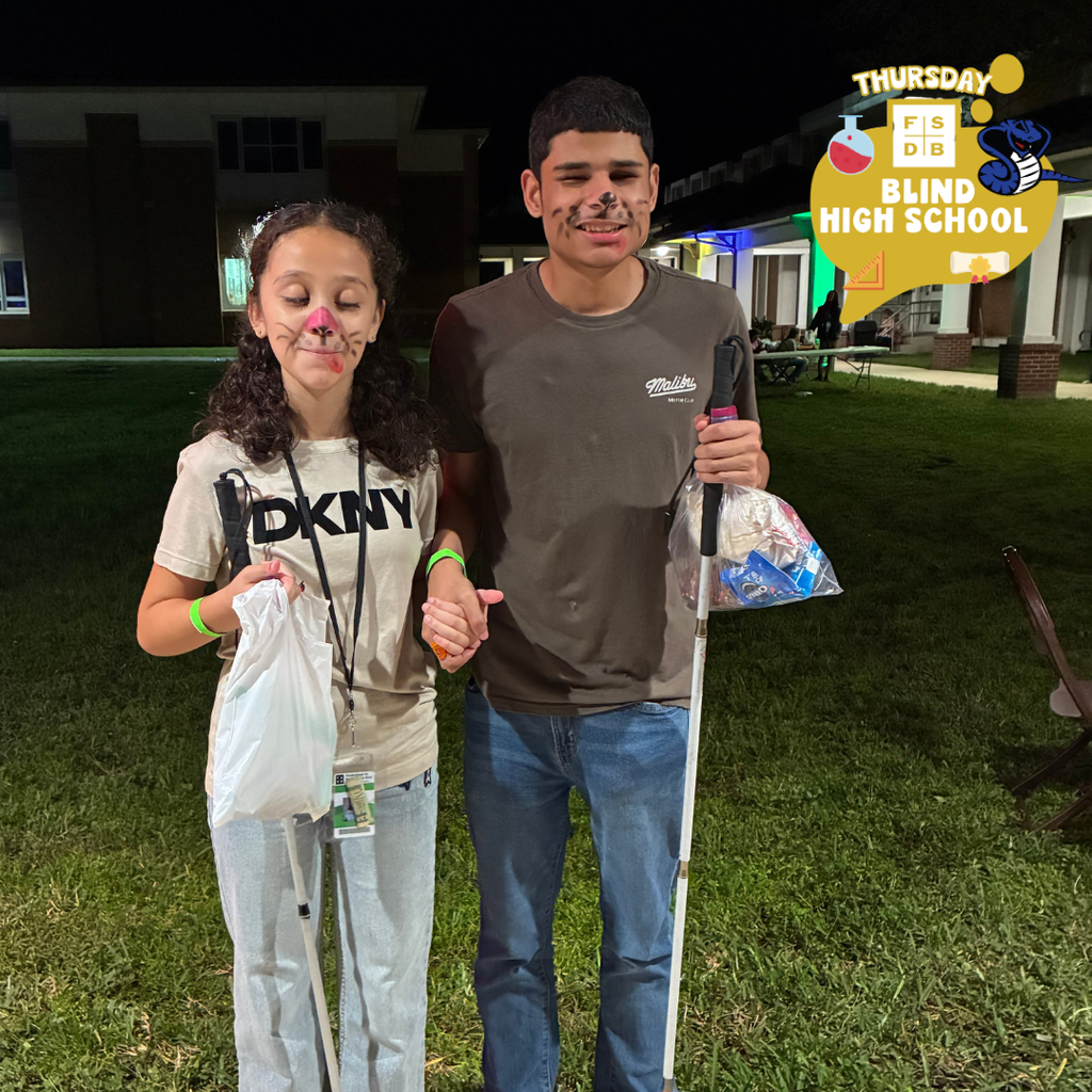 Two students face is painted and hold hands for their photo.