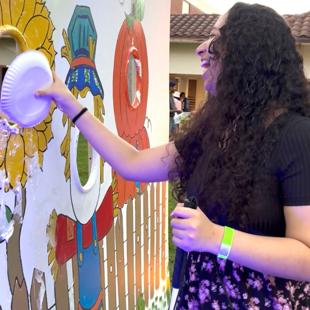 A student laughs as she pie faces a staff member.