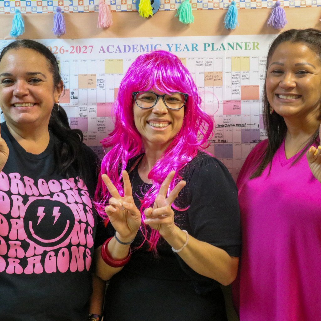 Three staff members dressed in pink and black.