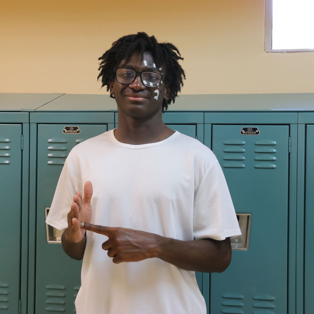 A student dressed in white and black sign "Junior" for the photo.