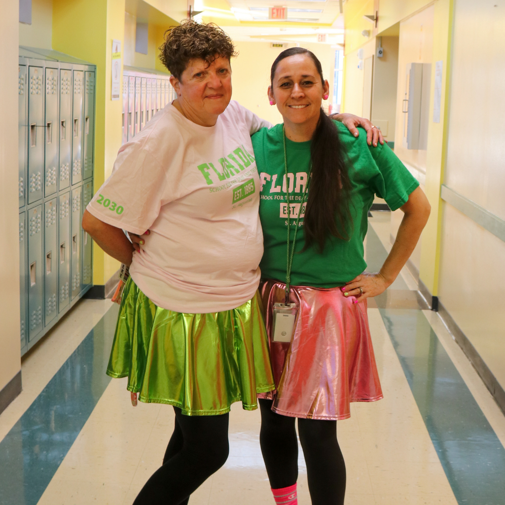 Two staff dressed in pink and green.