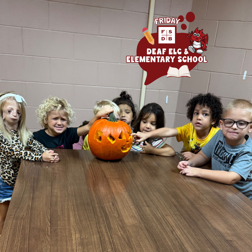 ELC students touch the pumpkin and smile for their photo.