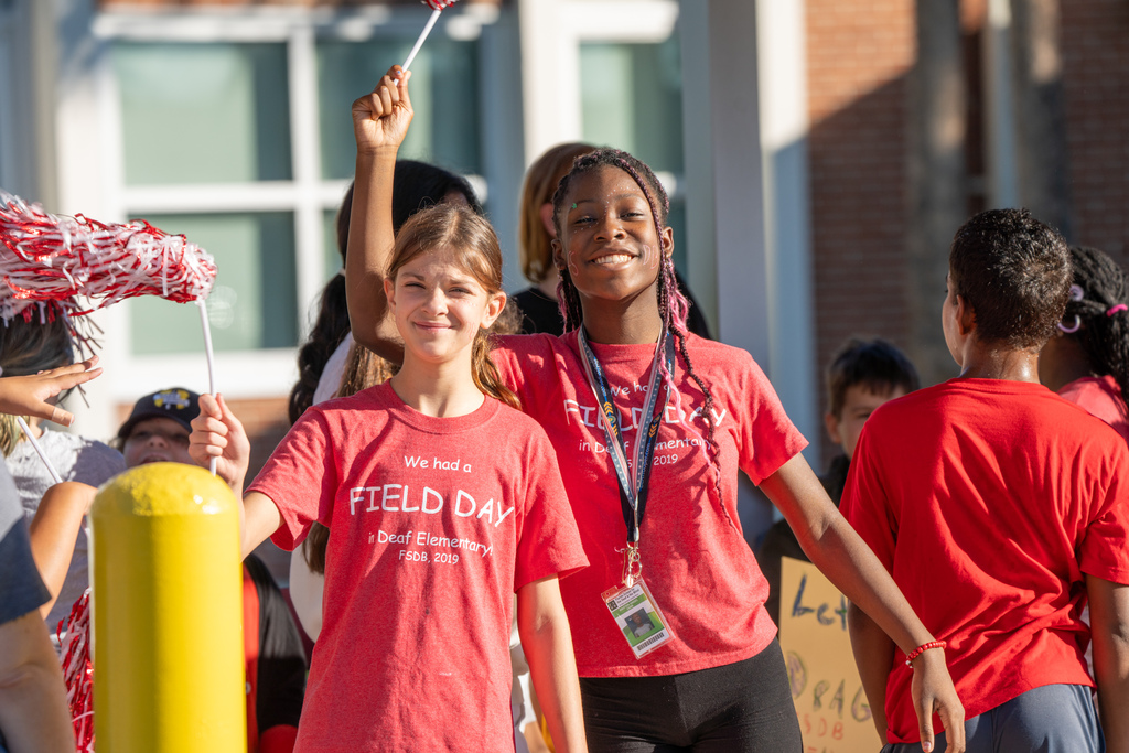 Two students are smiling outside waiting for the parade to start.