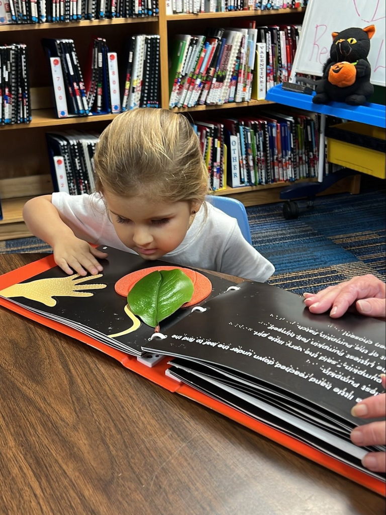 Luciana is listening and touching the different textures from the book "The Littlest Pumpkin".