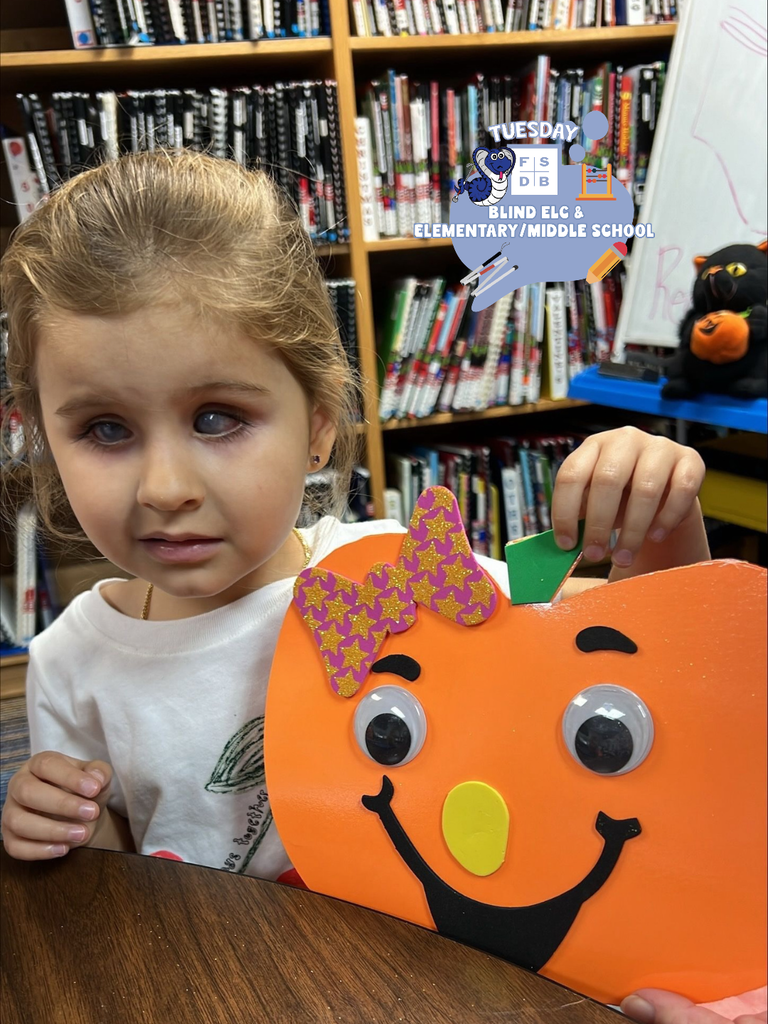 Luciana smiles with the pumpkin she made inside the library.