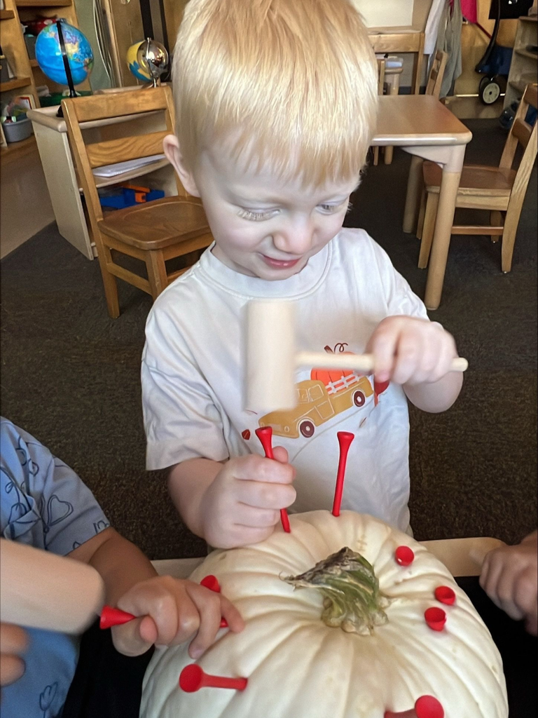 Jack smiles as he hammers golf tees into the pumpkin. 
