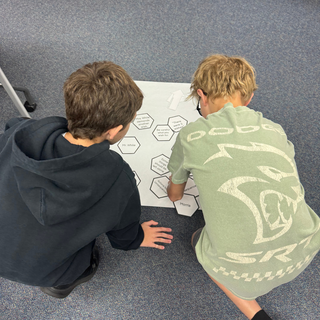 Two students sit together and work together to match cards inside the classroom. 