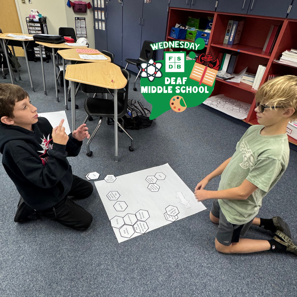 Two students kneel on the floor to discuss together the topic.