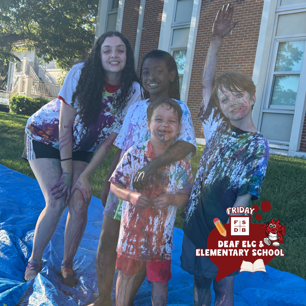 Students smile for a photo covered in washable dye. 