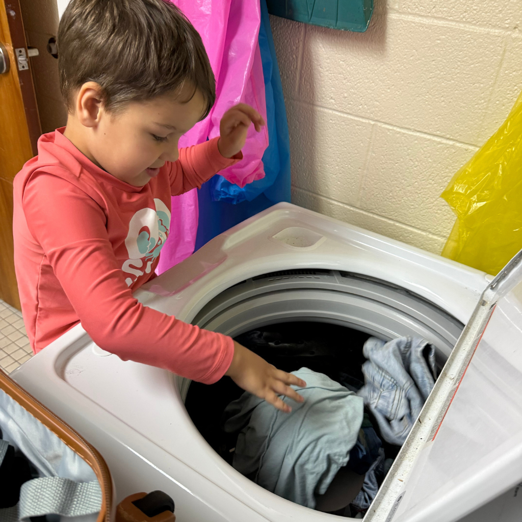 Student puts his clothes in the washer after. 