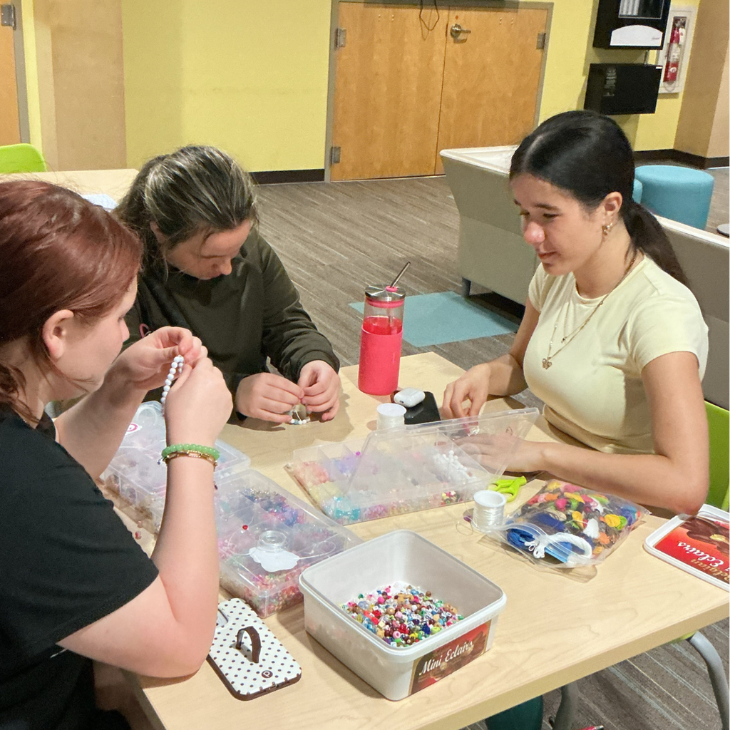 Three students work on a craft together inside the dorms. 