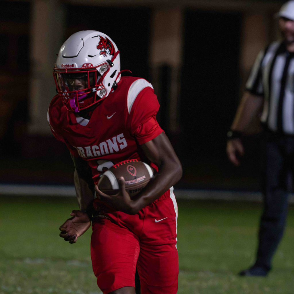 A FSDB football player runs with the ball in his hand on the field. 