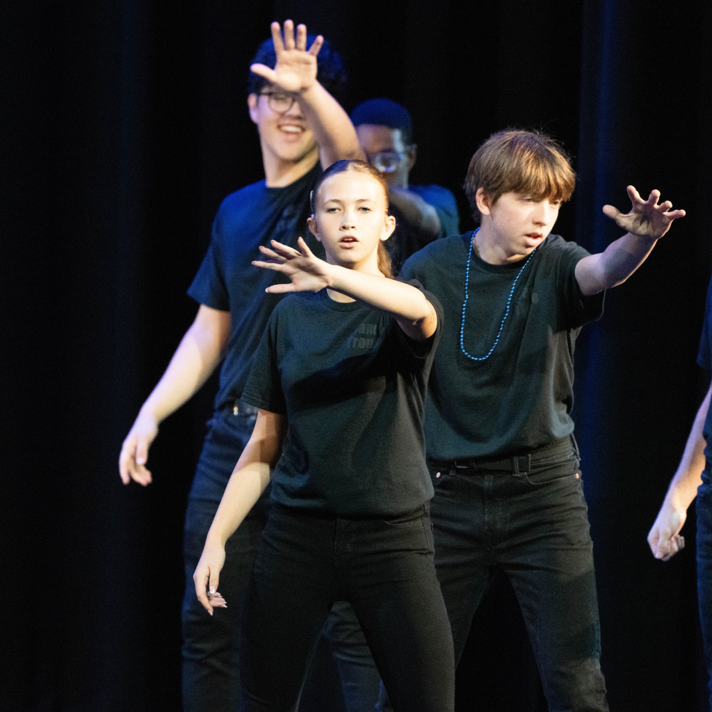 Three dance troupe performers on stage. 