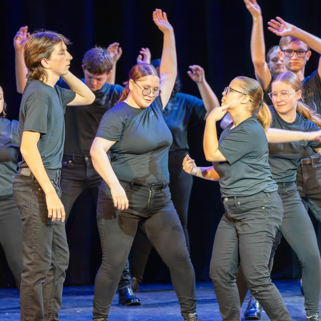 Group of dance troupe performers dance on stage. 