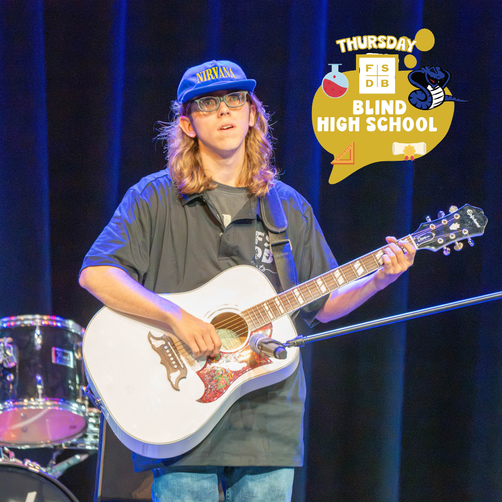 A student is playing the guitar on stage in Kirk for the audience.
