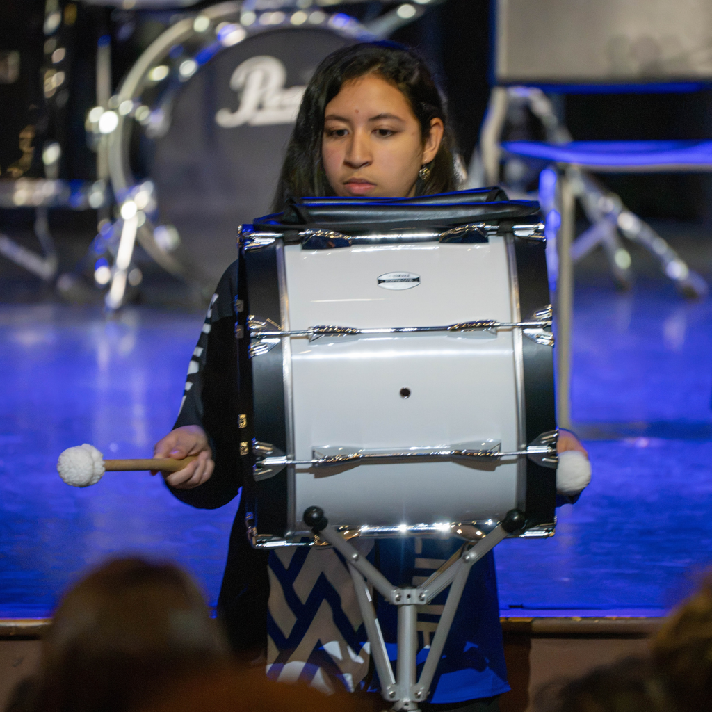 A student plays the drum for the audience in Kirk.