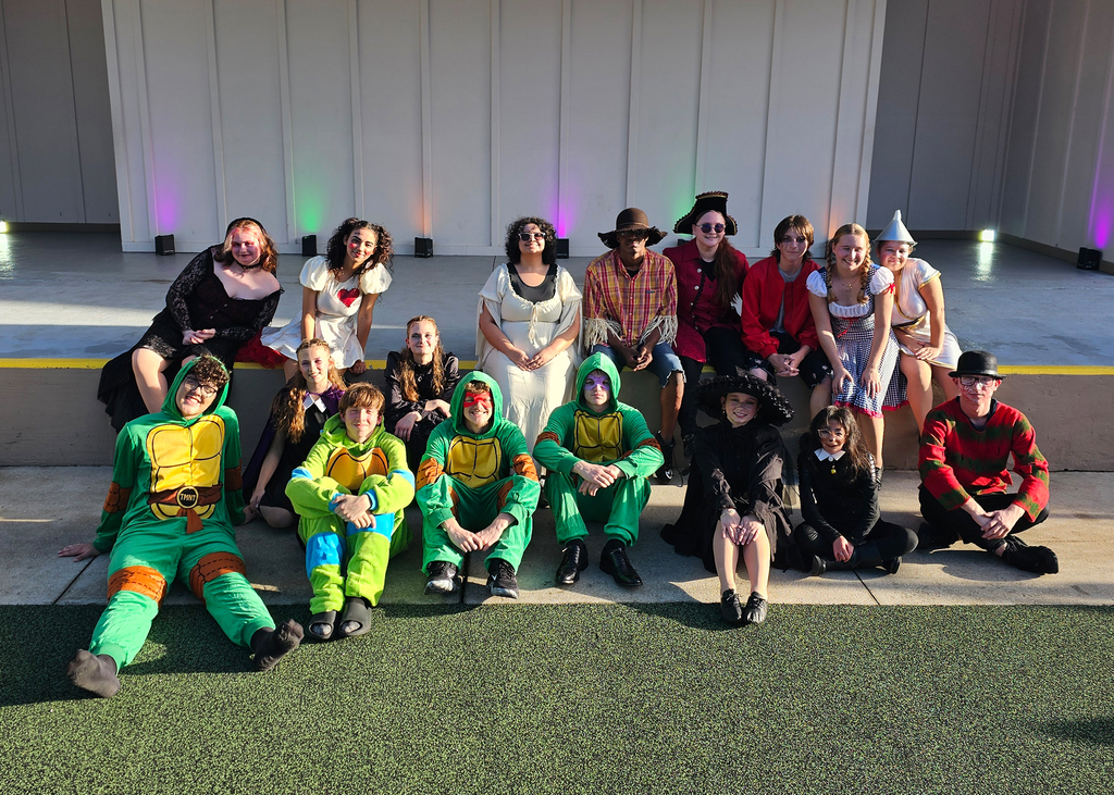 Group of Dance Troupe students dressed in costumes smiles for a photo by Kids Town. 