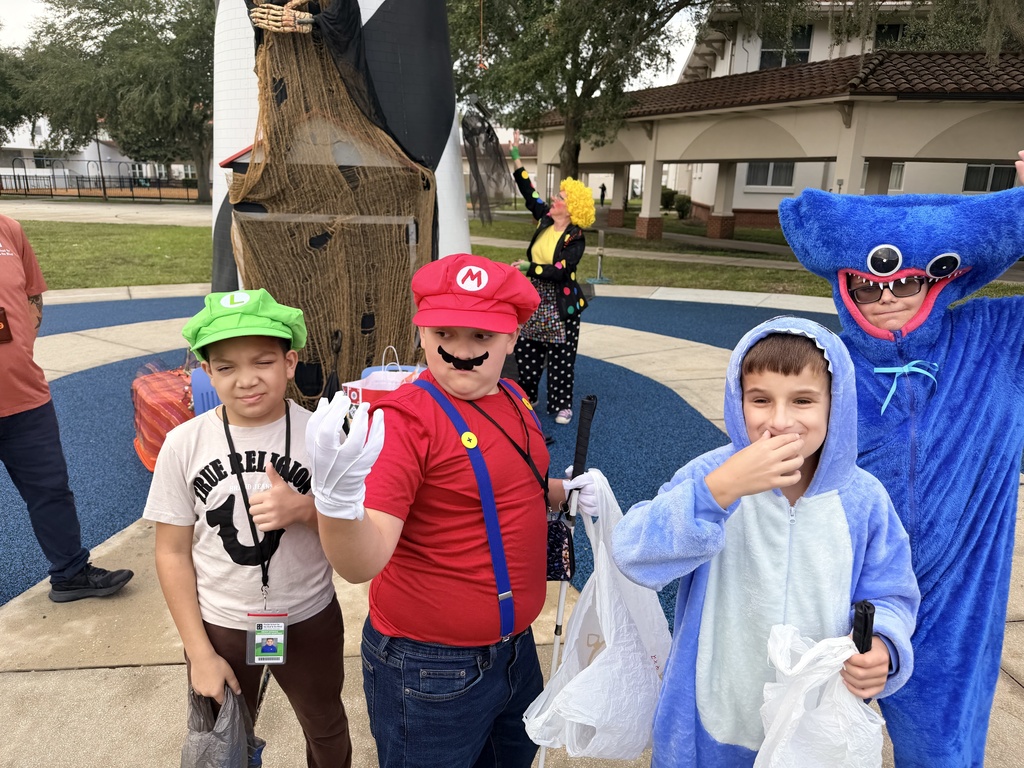 Few students dressed In costumes smile for a photo. 