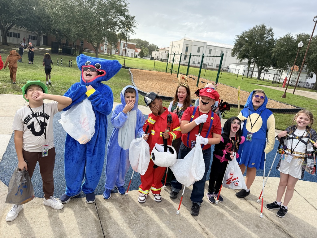 Group of students dressed in costumes smile for a photo. 