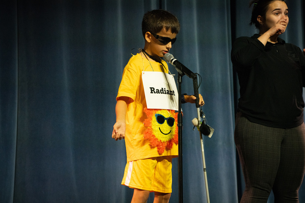 A boy dressed like the sun with yellow color and sign over his chest says "Radiant"