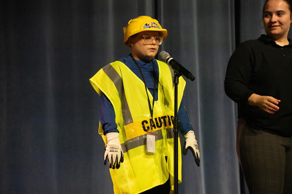 A boy dressed like a construction worker with the word "caution" on his stomach.