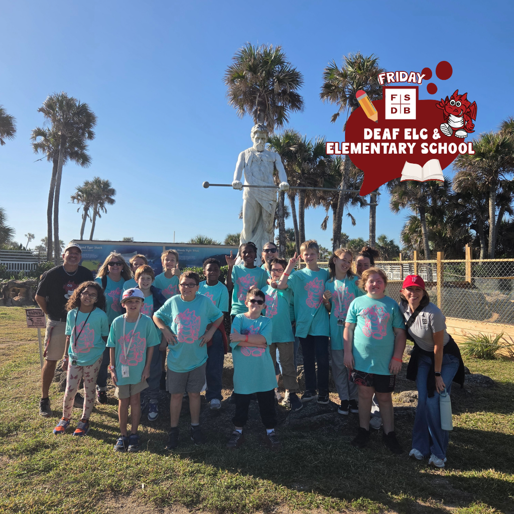 Group photo of the 4th grade class smile for a photo outside by a statue.