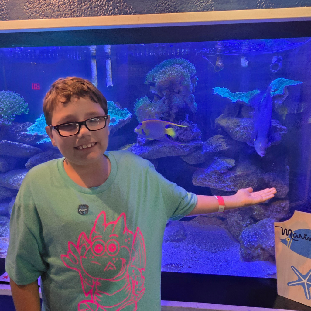 A student smiles with a fish in a tank.