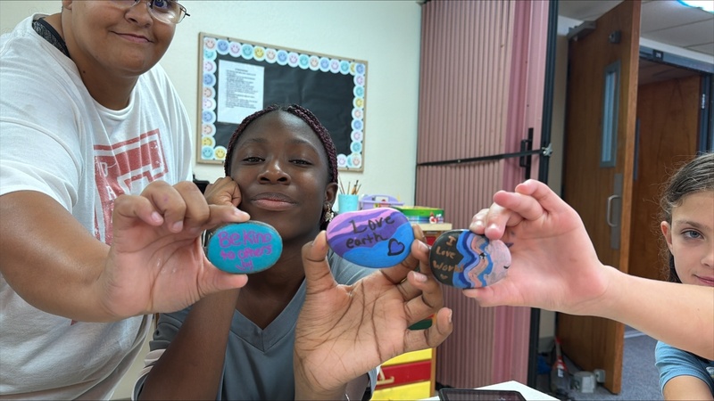 Students holding up colorful painted rocks