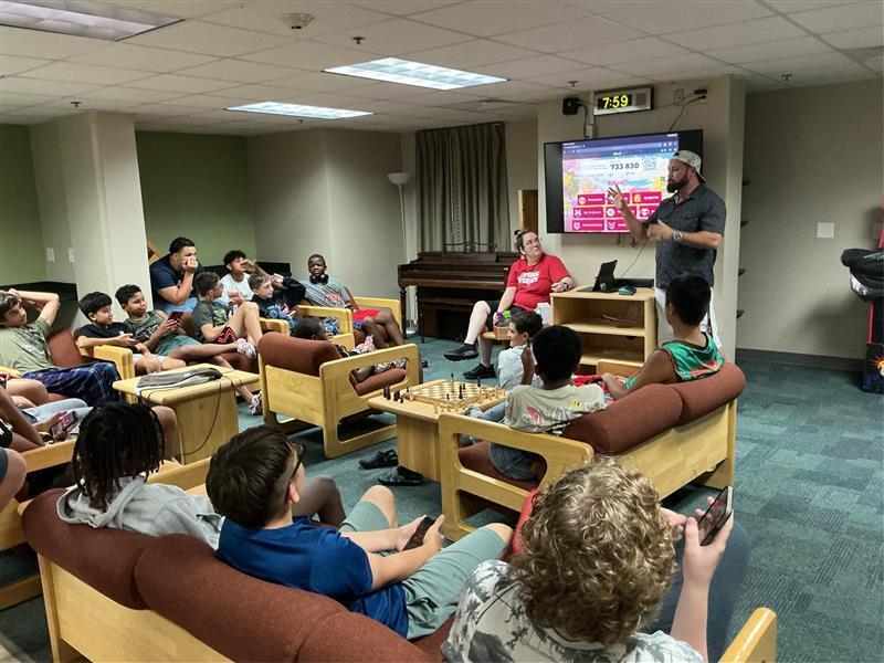 Group of boys sitting down playing trivia on television in dorm