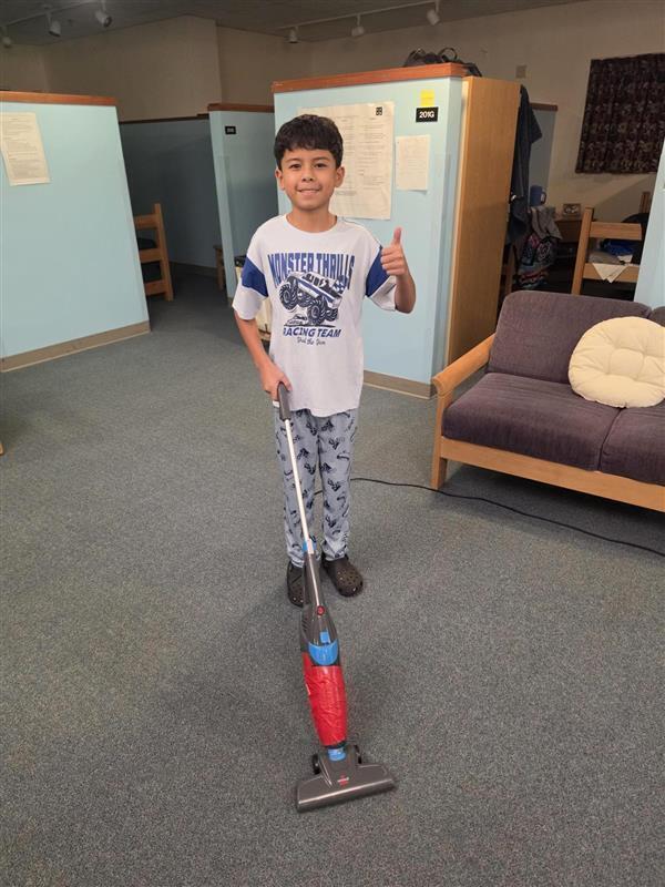 Boy student vaccuuming dorm