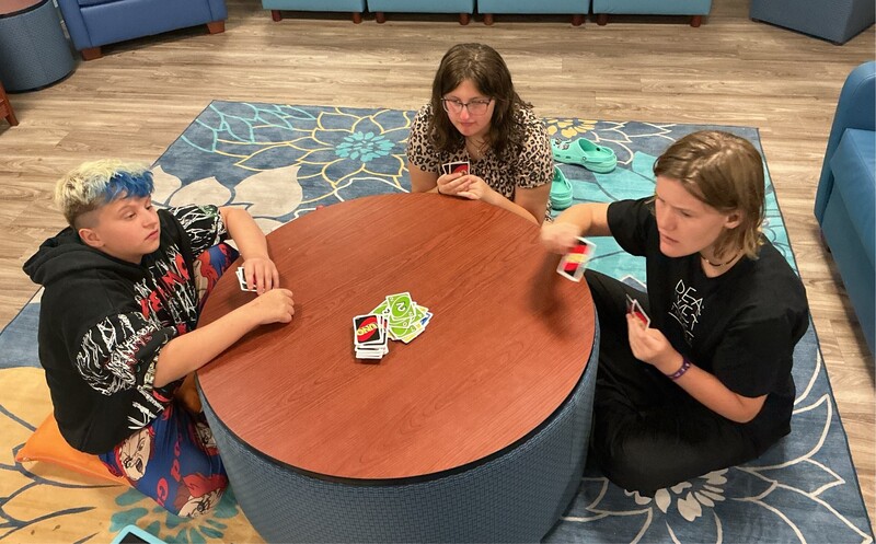 Group of students sitting around a round table playing Uno