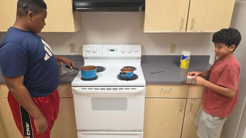 Two students cooking on the stove top.