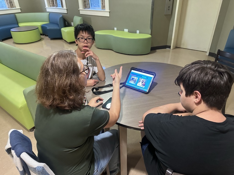 A staff member working with two students on a training exercise with an iPad.