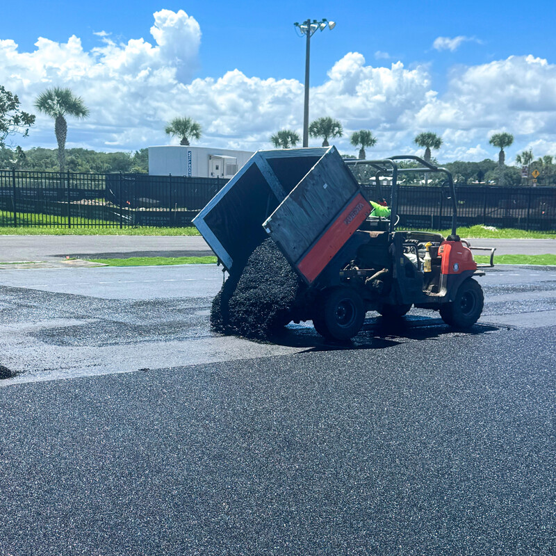 Rubber asphalt being poured out of a work cart in the high jump pit.