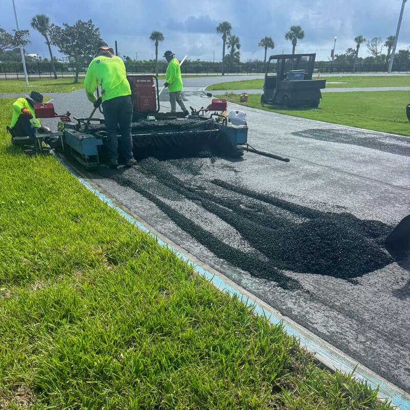 Workers laying new rubberized asphalt.