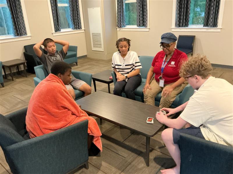 Student sitting around a coffee table playing Uno.