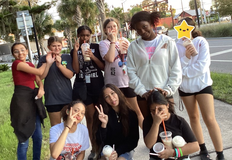 Group of girls posing for a picture with the Dunkin drinks.