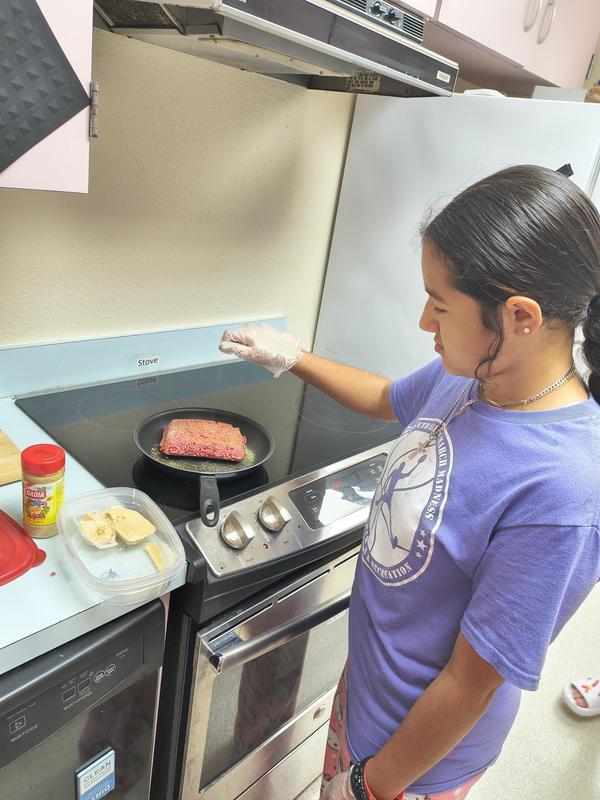 Girl cooking ground beef.